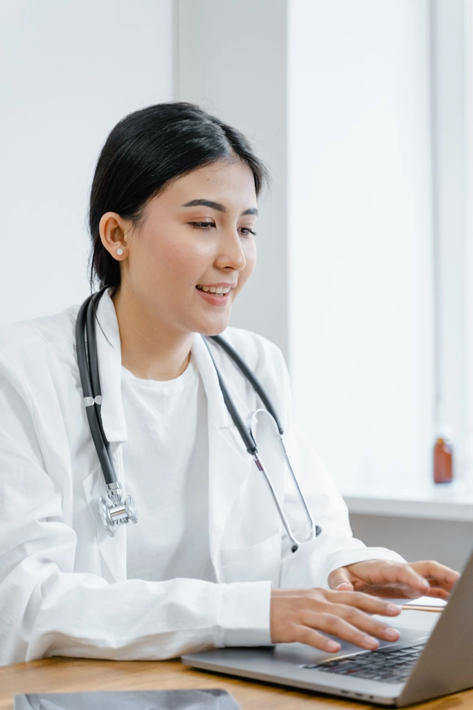 A doctor using a laptop in a clinical setting.